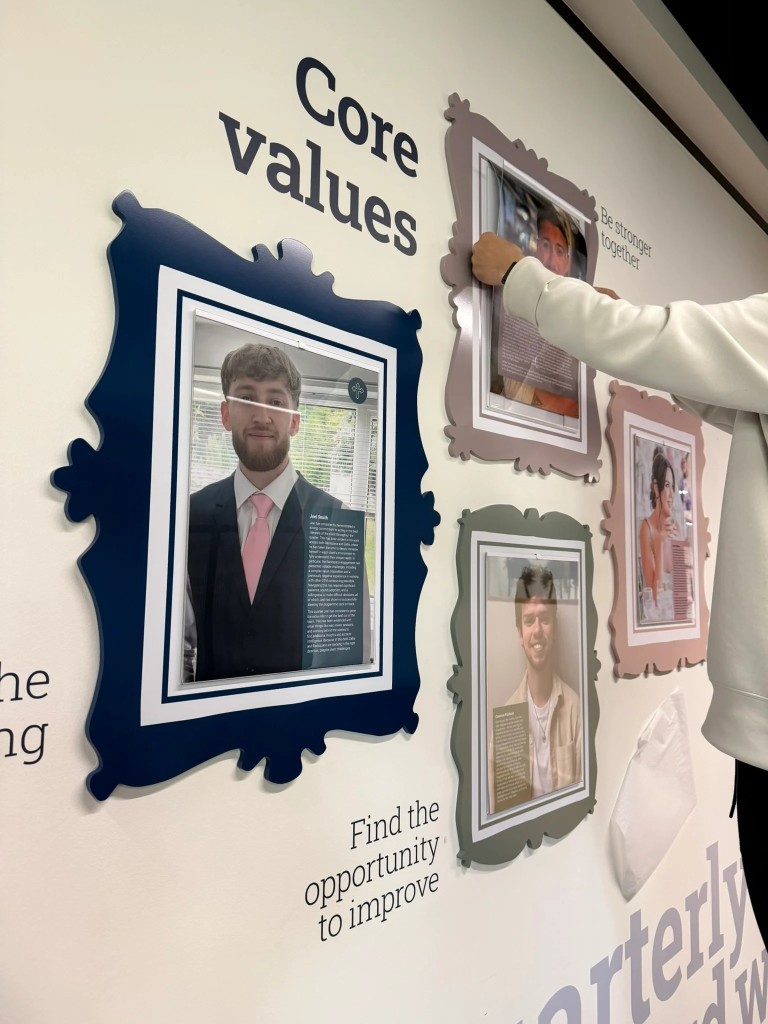 Core values wall display with framed portraits being installed indoors