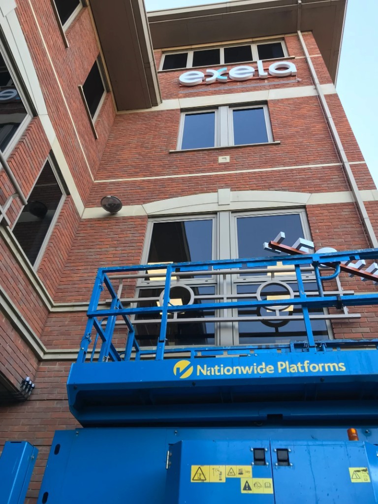 Cherry picker and platform during Exela exterior lettering installation
