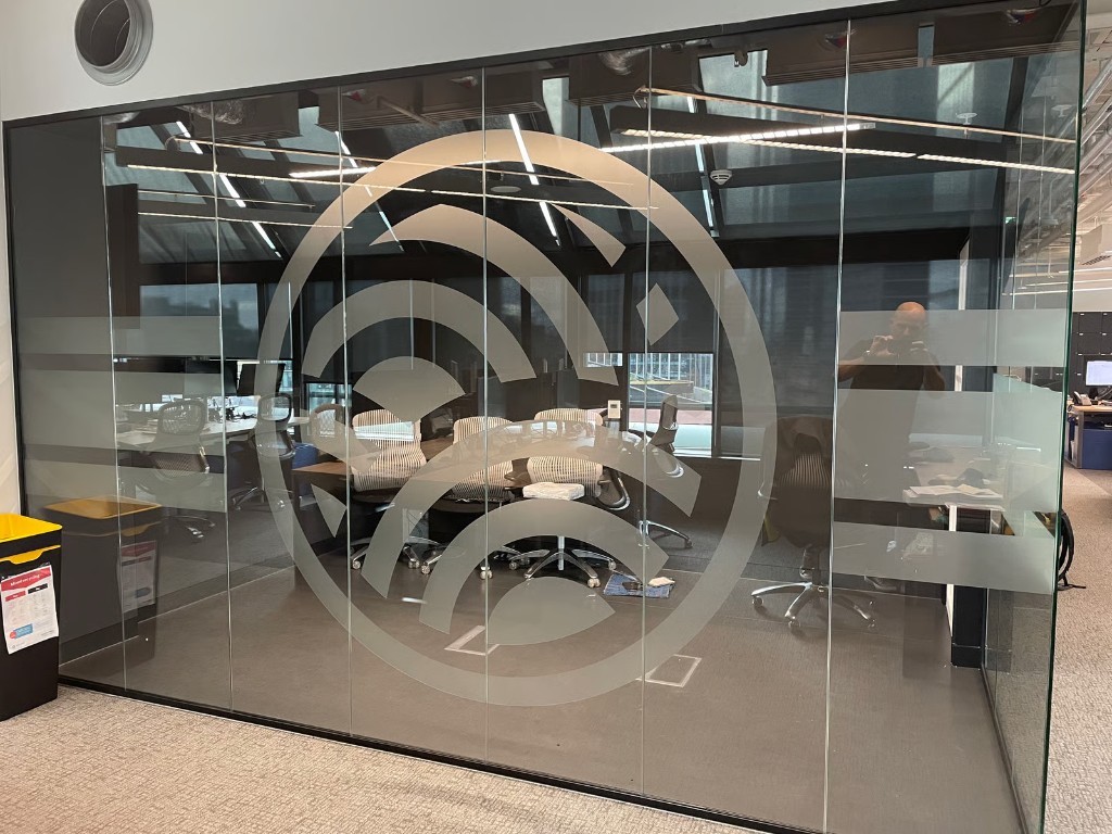 Circular frosted logo manifestation on a glass meeting-room wall