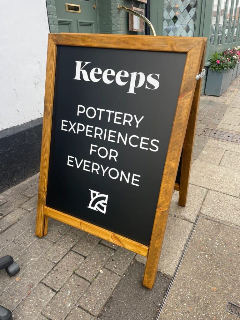 Keeeps pottery wooden A-board pavement sign on a shopfront sidewalk