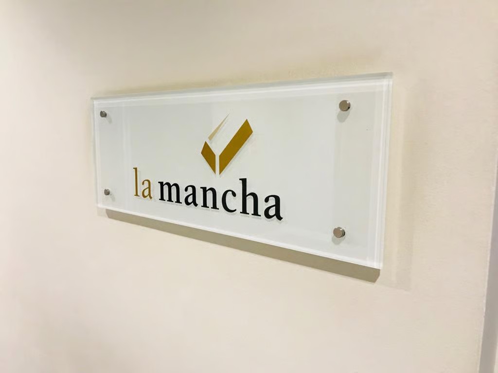 La Mancha clear acrylic plaque with gold logo on standoff fixings