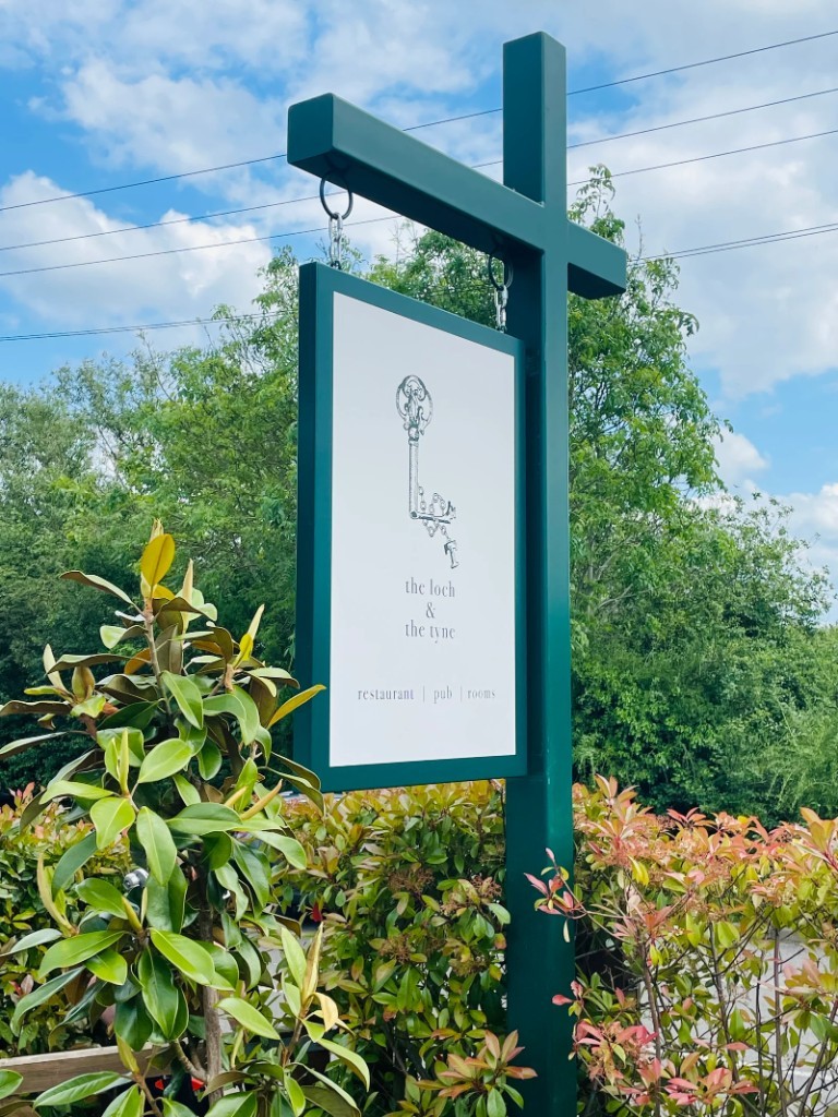 The Loch & The Tyne hanging projecting sign on a green post