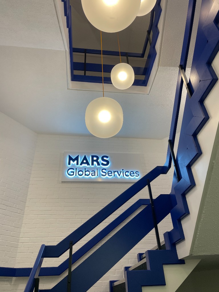 Illuminated Mars Global Services sign with halo-lit lettering in a corporate interior