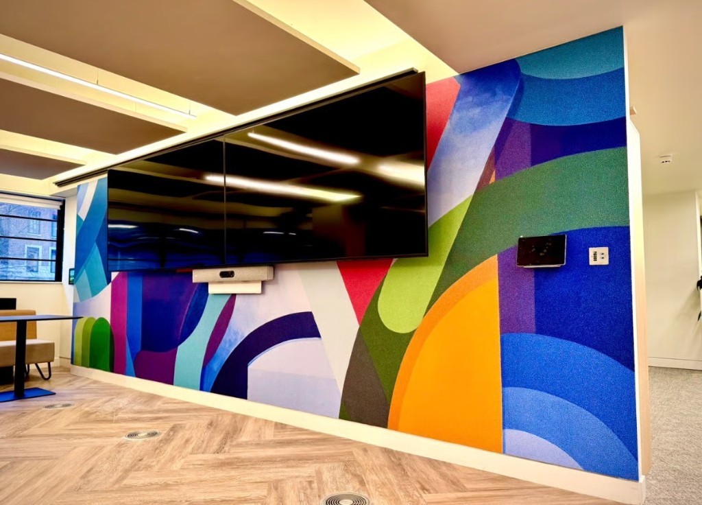 Branded office wall graphics around a meeting-room display