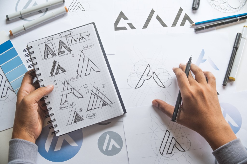 Graphic designer sketching logo concepts in a notebook