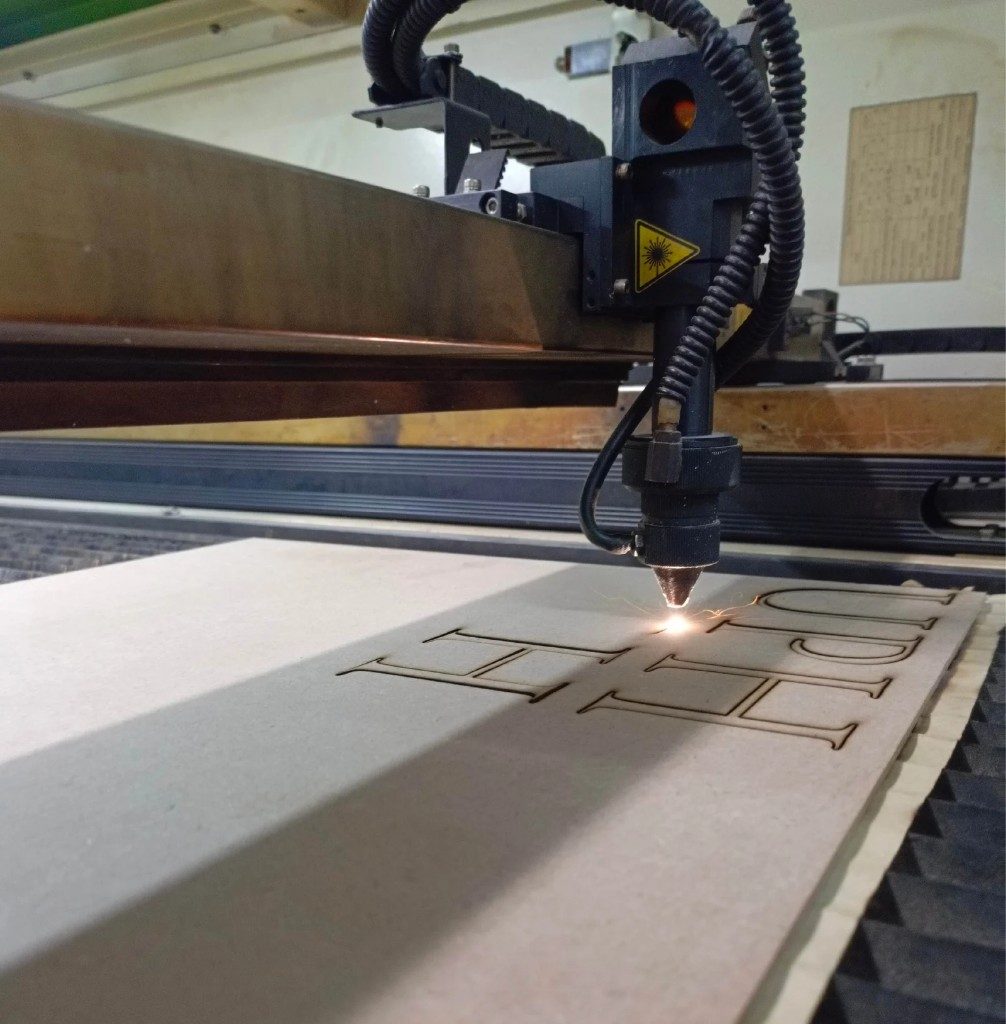 Laser cutter fabricating 3D lettering in the workshop