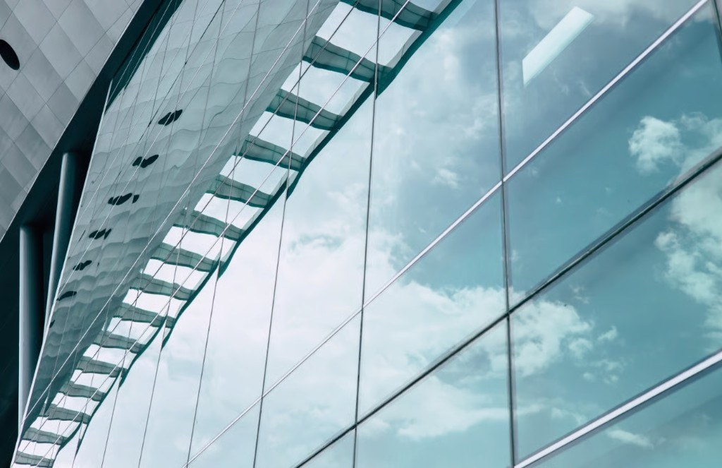 Modern glass facade reflecting sky, suited to solar and privacy window film